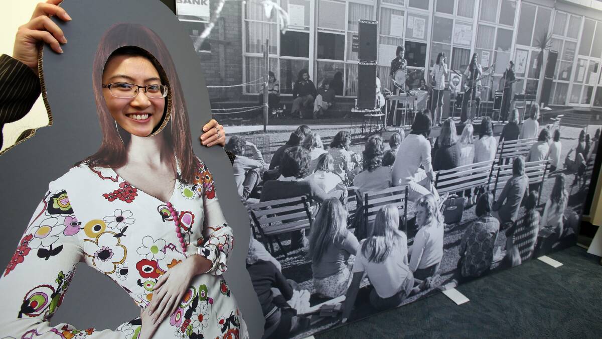 Looking back: Trang Dao tries a hippy-style cut-out for size at the exhibition marking 40 years of student life at UOW. Picture: KIRK GILMOUR