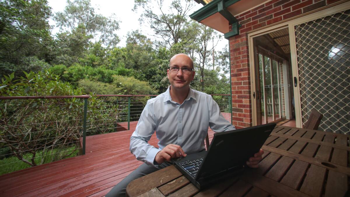 Joshua Marshall at his Figtree home. He has a long wait for the NBN  while homes over his back fence, left, are about to get access to the network. Picture: ADAM McLEAN