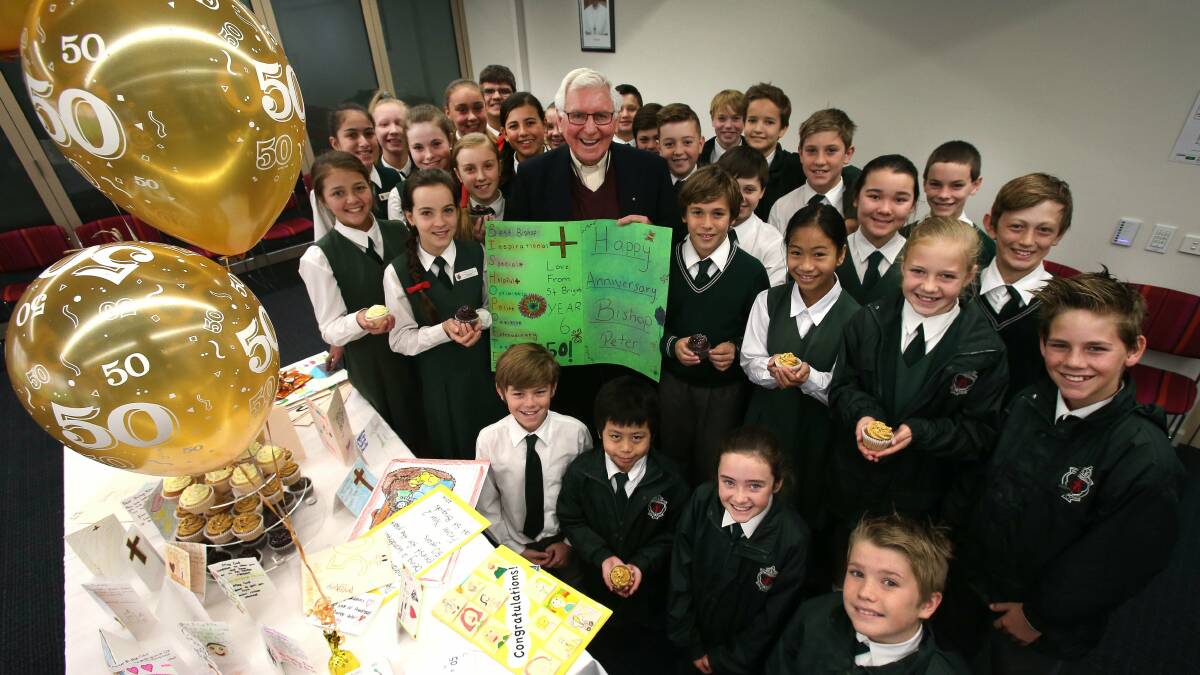 Mercury. News. Year 6 students from St Brigids Gwynneville presenting Bishop Peter Ingham with 50 cupcakes, a gift and cards to celebrate 50 years as an ordained priest at the Xavier Centre in Wollongong. Wednesday 16 July 2014. Story.Kate Walsh. Photo. Kirk Gilmour