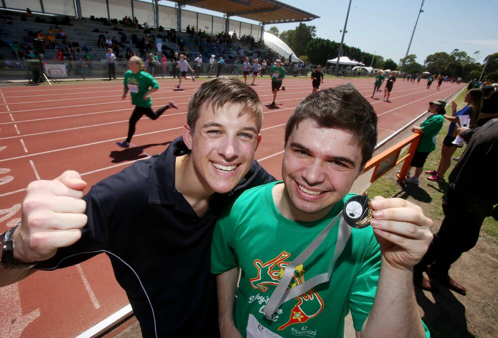 Volunteer and TIGS year 12 student Brady Rengger with Rocco Musumeci, 22, and his silver medal at the Sky's The Limit Mini Olympics on Thursday at Beaton Park. Picture: ROBERT PEET
