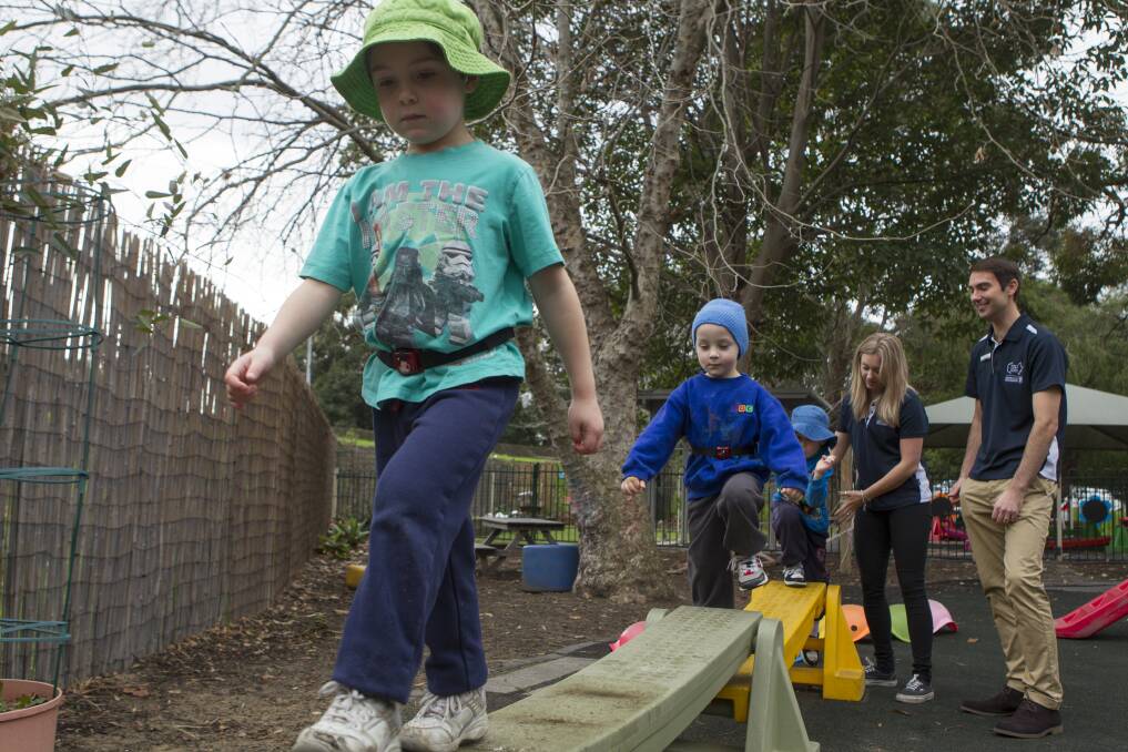 Outdoor fun: University of Wollongong researchers Jade McNeill and Dr Dylan Cliff watch preschoolers at Keiraview Children's Centre make use of an obstacle course. Picture: CHRISTOPHER CHAN