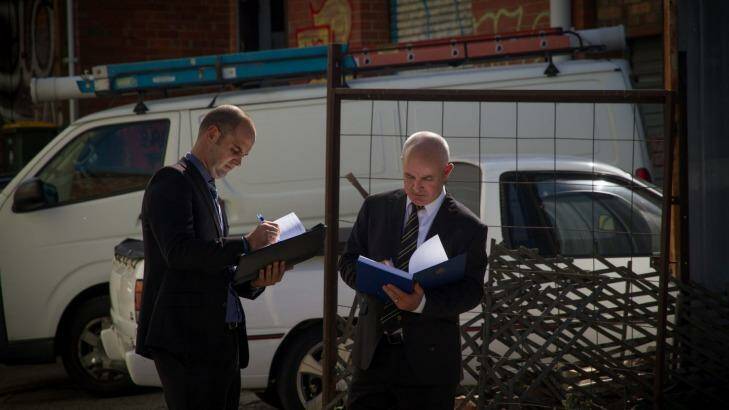Paul Rowe (left) and Dave Butler typify the public's idea of homicide squad detectives, carrying bound folders and wearing darks suits. Photo: Supplied