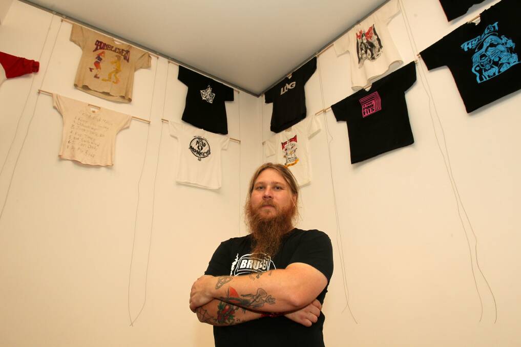 Steel City Sound exhibition curator Warren Wheeler with some band T-shirts at Wollongong Art Gallery. Picture: GREG TOTMAN