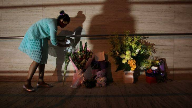 A young girl leaves flowers at the front of NSW Police Headquarters in memory of police employee Curtis Cheng. Photo: James Alcock