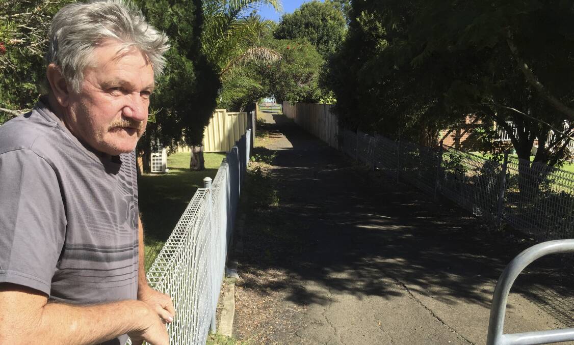 Unsafe: Resident Denis Taafe looks over his fence into one of the Warilla laneways which may be closed at night.