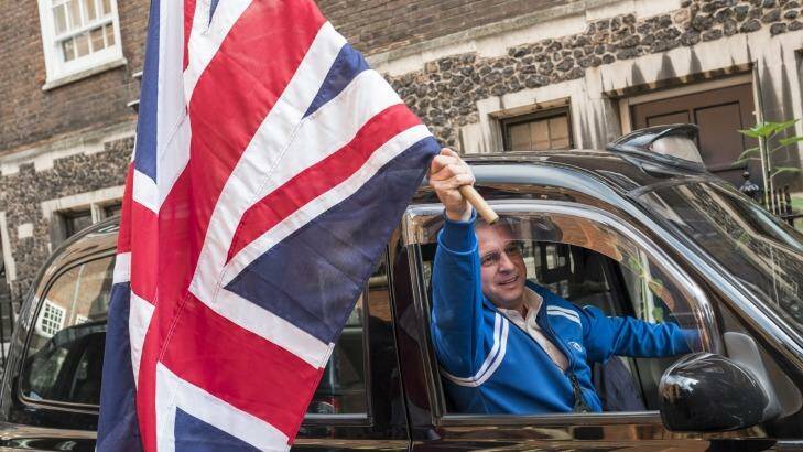 A British black cab driver triumphantly waves a Union Jack flag in London.  Photo: New York Times