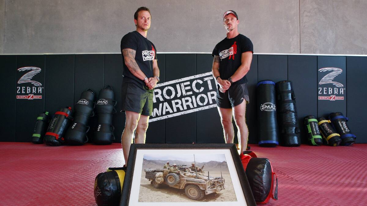 Former ADF commandos Shaun Trainor and James Gatley with a photo of three of their fallen mates. Picture: ANDY ZAKELI