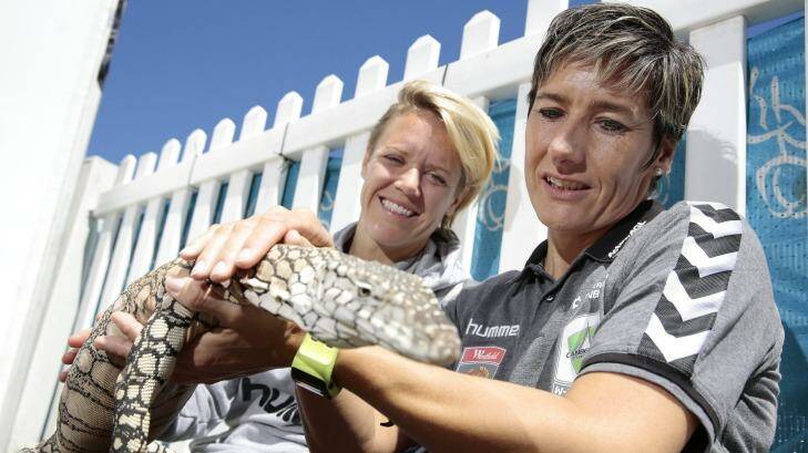 Canberra United player Lori Lindsey and coach Elisabeth Migchelsen get to know Cheeky the perentie at the Reptiles Inc display at Floriade.  Photo: Jeffrey Chan