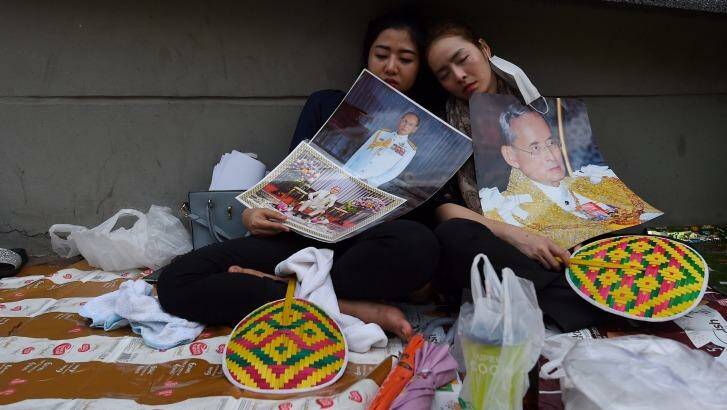 Dressed in black for mourning, two women sleep on the footpath outside Siriraj Hospital in Bangkok following the death of Thai King Bhumibol Adulyadej. Photo: Kate Geraghty