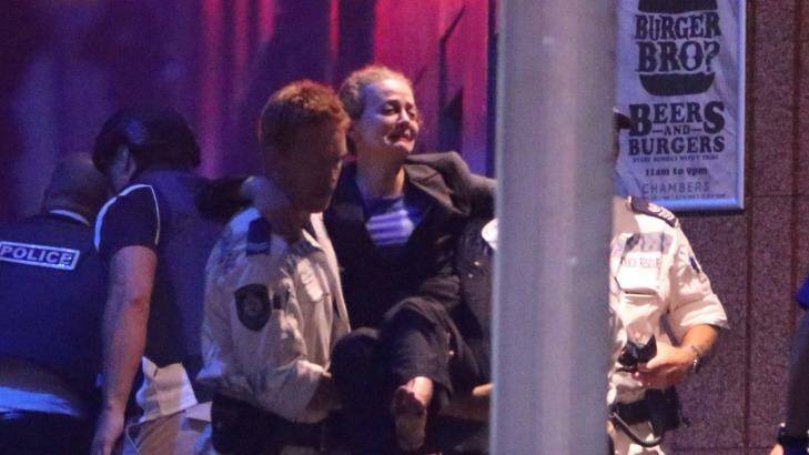 Hostage Marcia Mikhael is assisted from the Lindt Chocolat Cafe in Martin Place. Photo: Andrew Meares