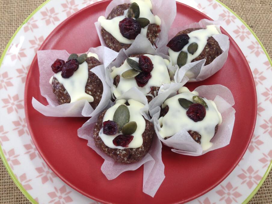 Raw Christmas puddings are easy-to-make festive bites. Pepitas and cranberries are used as the holly.