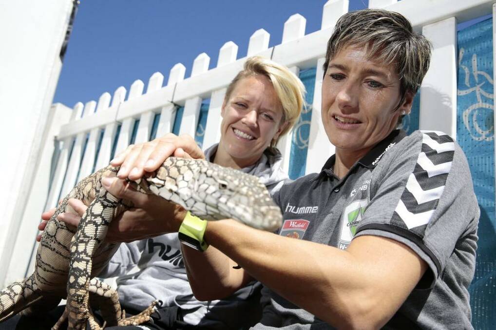 Canberra United player Lori Lindsey and coach Elisabeth Migchelsen get to know Cheeky the perentie at the Reptiles Inc display at Floriade.  Photo: Jeffrey Chan