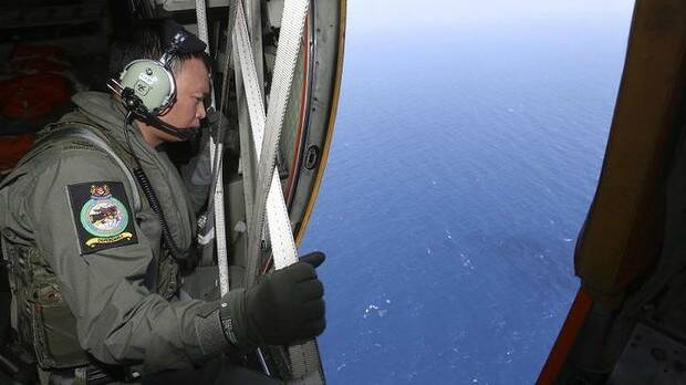 A member of the military personnel looks out of a Republic of Singapore Air Force C-130 transport plane during the search for the missing Malaysia Airlines MH370 plane over the South China Sea. Picture: REUTERS