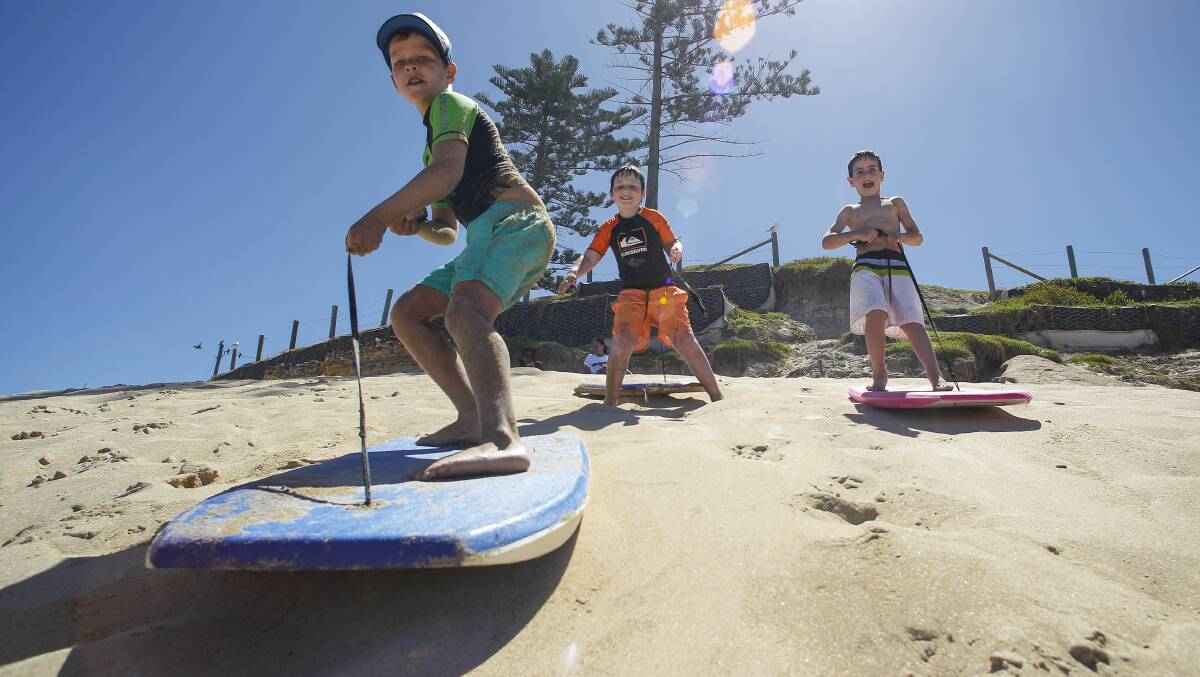 Eli, 7, Keegan, 7 and Cooper, 6 surfing the sand at Bulli Beach. Picture: CHRISTOPHER CHAN