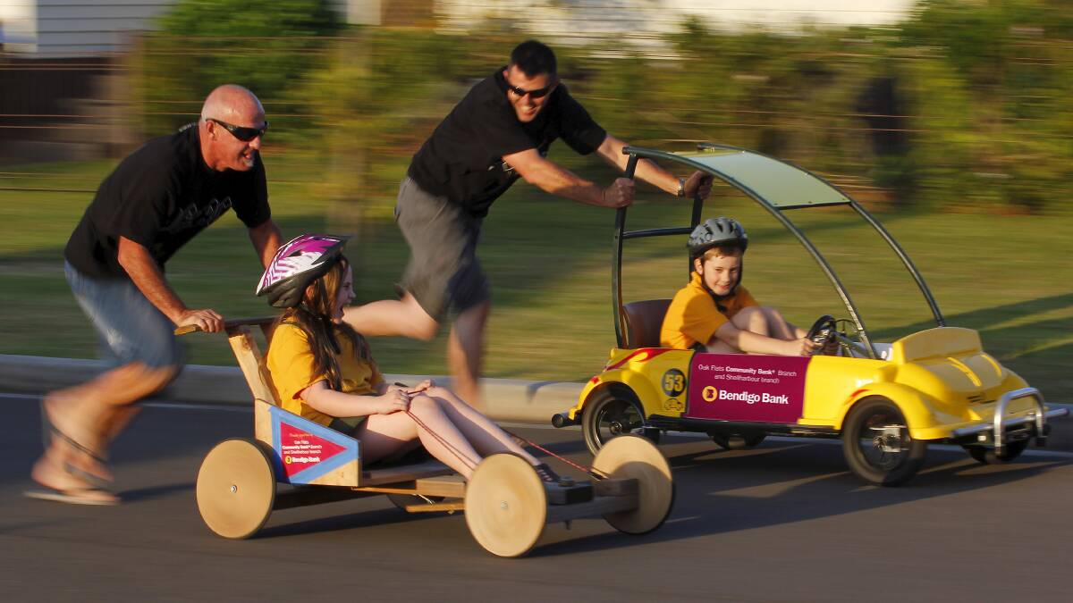 Mark Tolley (left) and  Michael Austin give Oak Flats Public School kids Hannah Austin and Thomas Cormack a test ride in a couple of the carts. Picture: ANDY ZAKELI