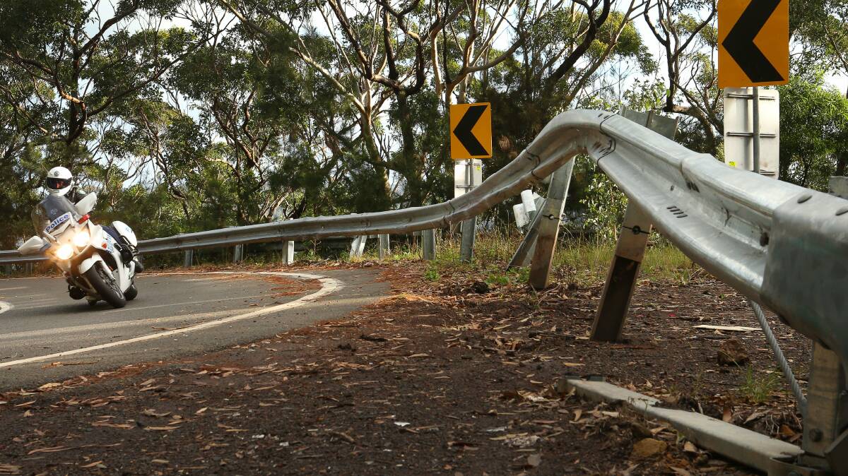 Wollongong Highway Patrol supervisor sergeant Stewart Arnold passes a damaged Armco road barrier on Lady Wakehurst Drive near Otford. Picture: KIRK GILMOUR