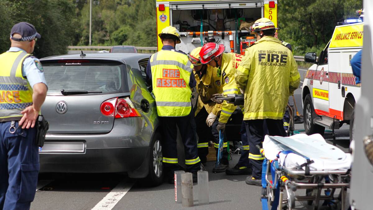 Emergency crews work to free a woman trapped in her car at Figtree on Tuesday. Picture: CHRISTOPHER CHAN.