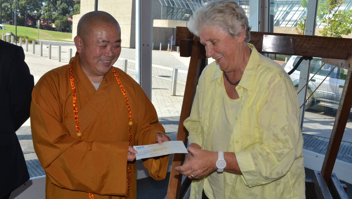 Shaolin Abbot Shi Yongxin presents a bank cheque to Shoalhaven Mayor Joanna Gash for $4,162,723.99 to finalise the mortgage payments for the Comberton Grange property at Falls Creek.