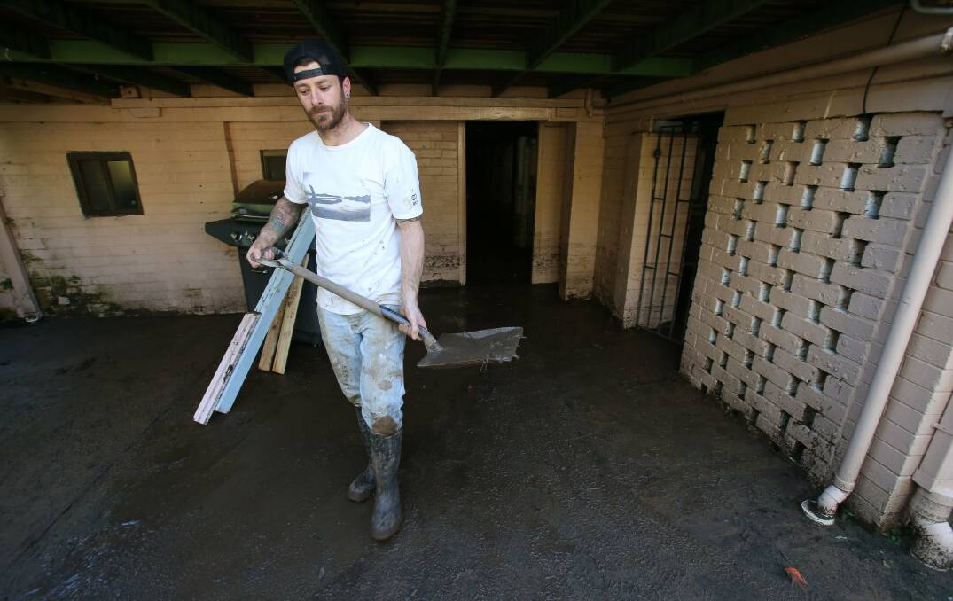 Thirroul resident Phil Devlin moves mud from underneath his home in Lachlan Street.