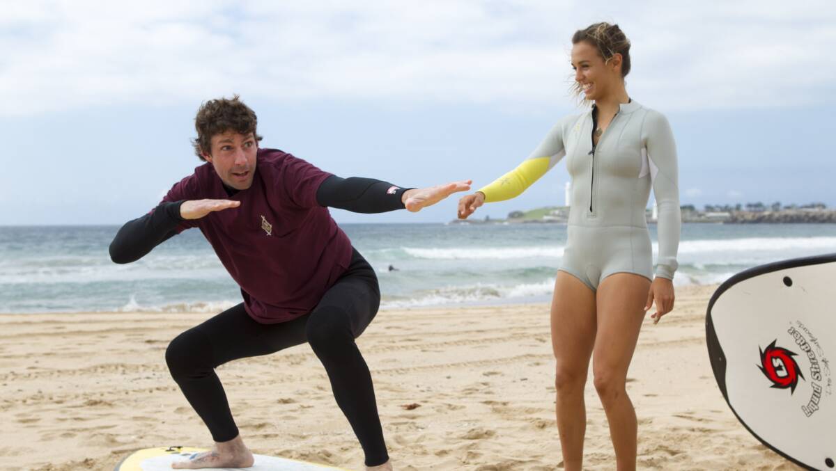 Sally Fitzgibbons gives Travis Pastrana a surfing lesson at Wollongong North Beach on Thursday.  Picture: CHRISTOPHER CHAN