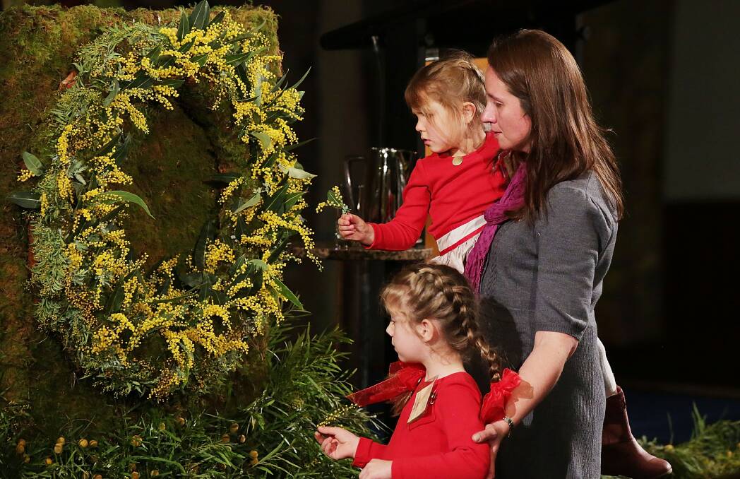 Family members place wattle on a wreath in a memorial service for victims of flight MH17. Picture: Getty Images