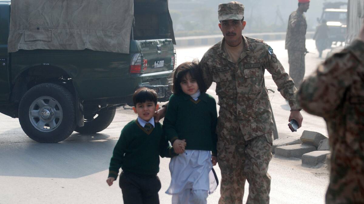 A soldier escorts schoolchildren from the Army Public School after an attack by Taliban gunmen in Peshawar. Picture: REUTERS