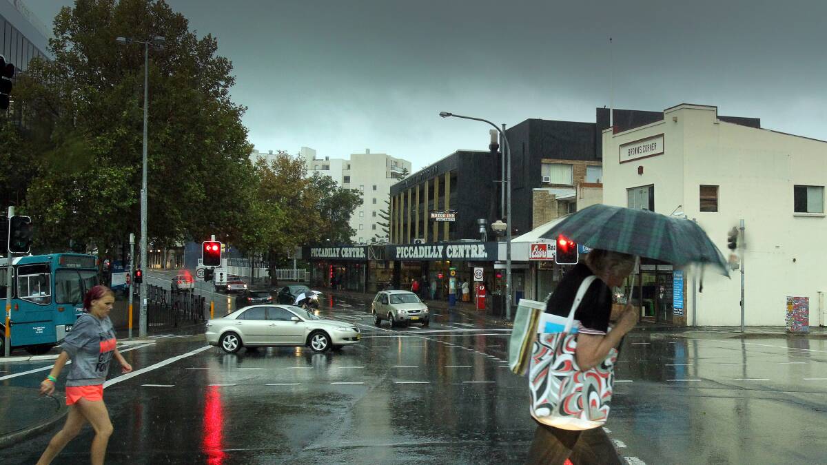 Pedestrians run for cover in Crown Street, Wollongong, as a deluge hits. Picture: KIRK GILMOUR