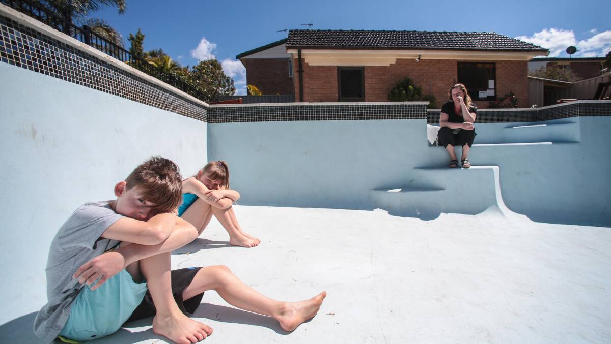 Bellambi resident Sandra Cram with her children Daniel and Zoe  in their empty concrete pool. They have waited seven months for it to be repaired. Picture: ADAM McLEAN 