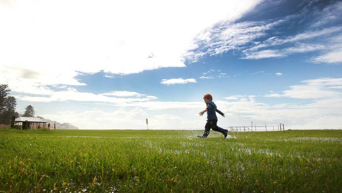 Lachlan Ireland makes the most of the saturated grass at Thirroul Beach as the blue sky began to return to the Illawarra. Picture: SYLVIA LIBER