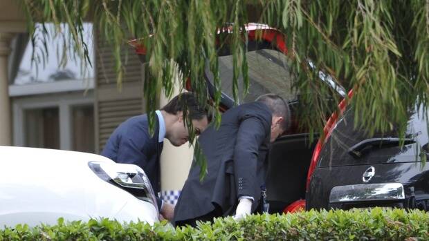 Police examine the boot of a car outside the home of Phil Walsh on Friday. Picture: GETTY IMAGES