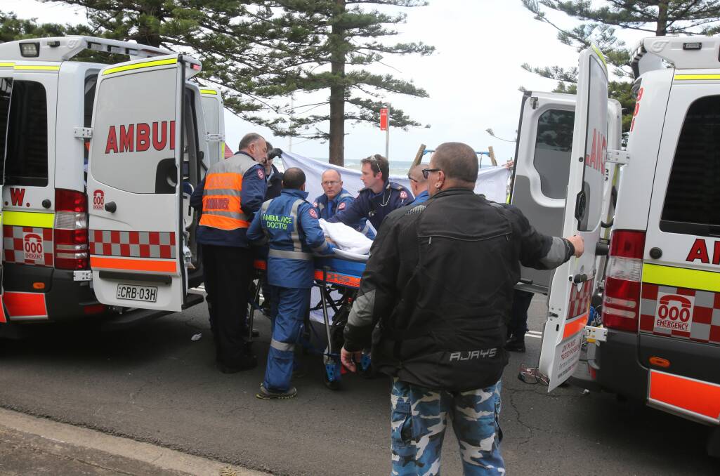 Emergency services move an injured man to the waiting ambulance after an accident on Lawrence Hargrave Drive on Saturday. Picture: supplied