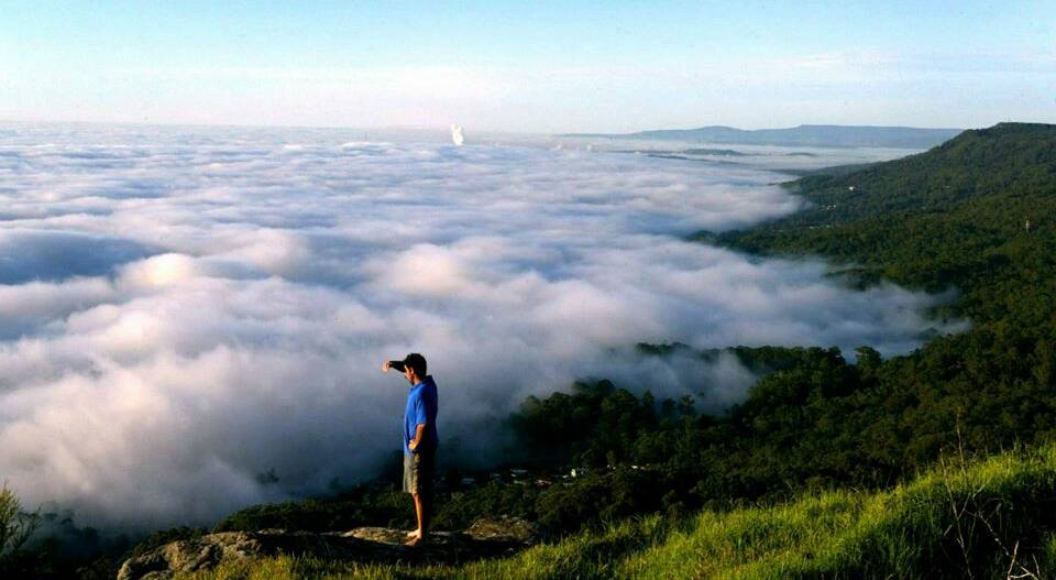 Ron Gammone of Woonona stands on a rocky outcrop near the Panorama House, Bulli Tops, as a fog blankets the Wollongong region. 