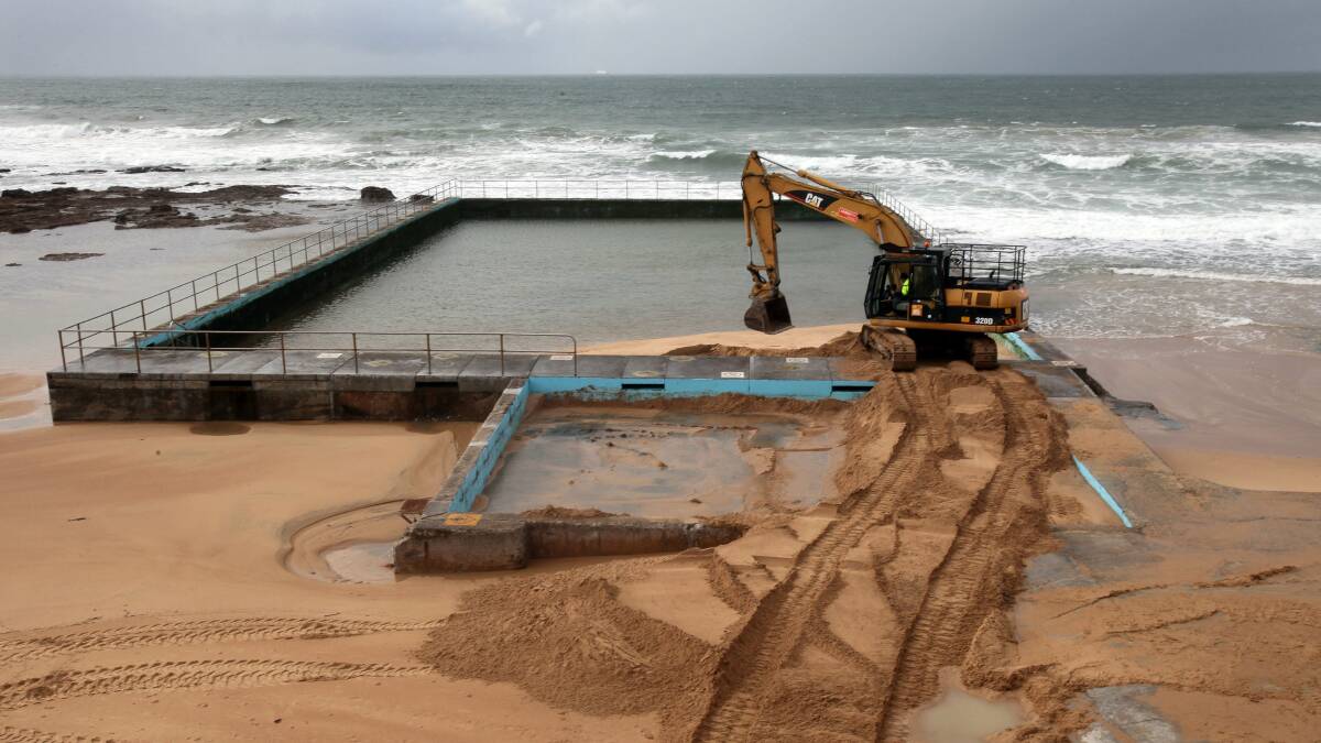 An excavator removes buckets of sand from Bulli ocean pool. Pictures: KIRK GILMOUR