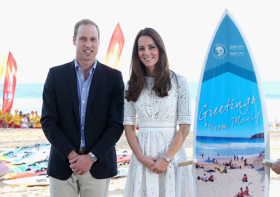 The royals pose with a surfboard they were given as they attend a lifesaving event at Manly Beach. Picture: GETTY IMAGES