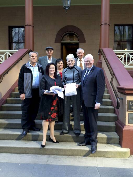 Stop the Hub members (back) Paul Hockey, Allan Chaseling, Anna Lukies, Harry Lukies and (front) Diane Quinlin present a petition to Shellharbour MP Anna Watson (front) with Kiama MP Gareth Ward. 