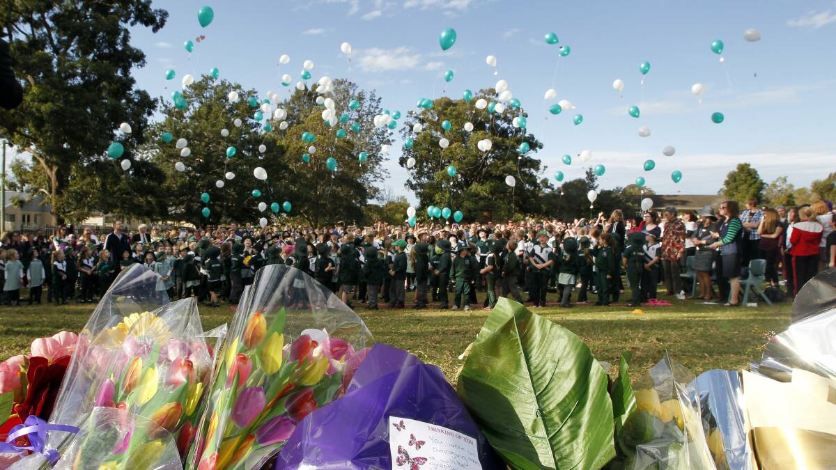 Friends, family and members of the community release balloons at a public memorial at Albion Park Public School for Michael and Carol Clancy on Friday.