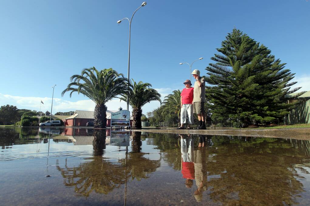 Laurie and Cathy Bridge inspect the flooded entrance to Port Kembla Golf Club. Picture: SYLVIA LIBER