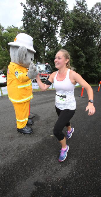 Mission accomplished: Smokey congratulates Melanie Law, of Woonona, at the Mount Keira Challenge finish line. Picture: Robert Peet.
