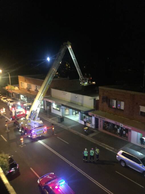 Fire and Rescue NSW crews work to retrieve the man from the roof of a Corrimal business on Wednesday night. Picture: Scott Loughland