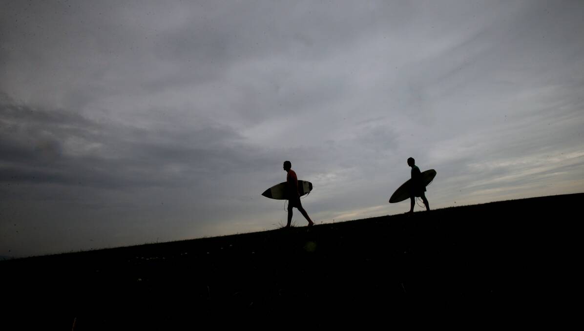 GLOOMY: Surfers are silhouetted against a grey sky at Bulli. Wollongong is experiencing above average rainfall this month and more is on the forecast. Picture: Sylvia Liber