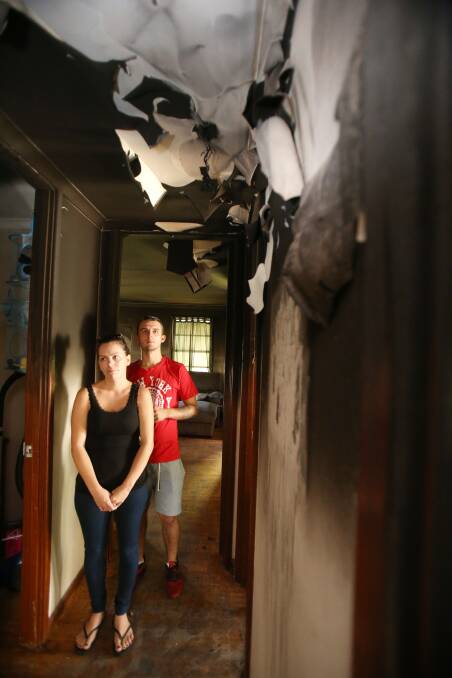 Jasmine O’Malley and Callum Taylor in what's left of their Unanderra home after a fire on Monday night. The couple's son, three-year-old Cohen, had been playing with a lighter when the fire started. Picture: Robert Peet