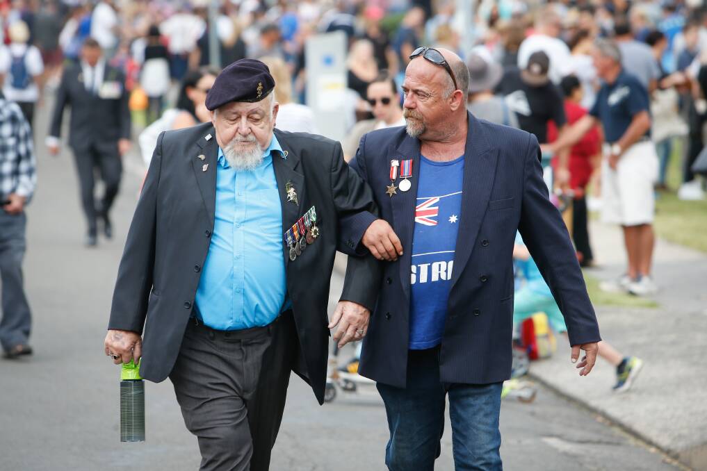 Glenn (surname not provided) helps Ray St Quintin walk along Chruch Street after the Wollopngong Anzac march on Tuesday. Picture: Adam McLean