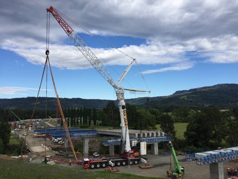 A 500-tonne crane lifts the first of 228 girders onto the new Berry bridge, which  forms part of the $580 million Foxground and Berry bypass, on Friday morning. Picture: Adam Wright