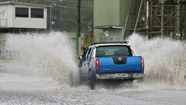 A motorist driving through water in Unanderra. Picture by Adam McLean