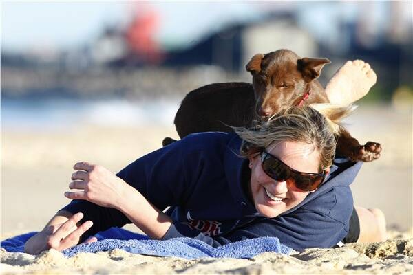 Stephanie Clingan of Shellharbour and her three-month-old kelpie, Arnold, play on Coniston Beach yesterday. Picture: DAVE TEASE
