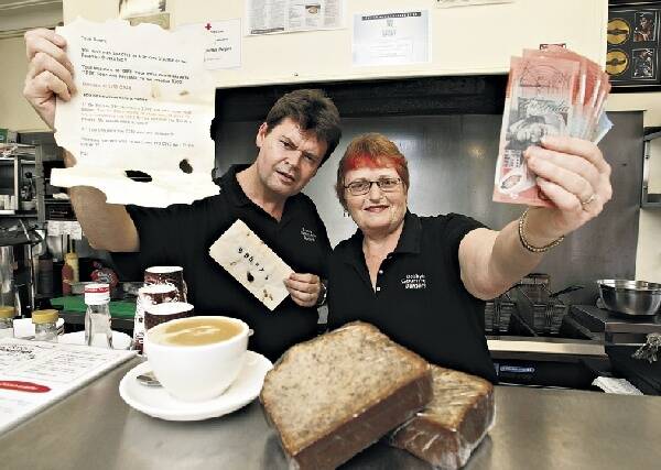 Bobby's Gourmet Burgers proprietor Darrell Pitt and his wife Cleo with the envelope they found under their door. Picture: DAVE TEASE