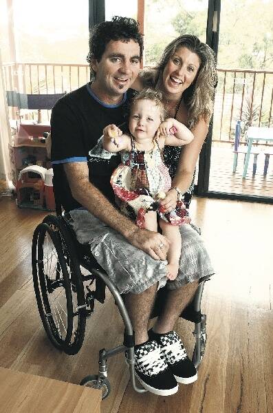 Injured surfer Darren Longbottom gets a cuddle from daughter Bowie and hug from wife Aimee after returning home after spending many months in a spinal unit at Ryde Hospital. Mr Longbottom broke his neck in a surfing accident in Indonesia.Picture: ROBERT PEET