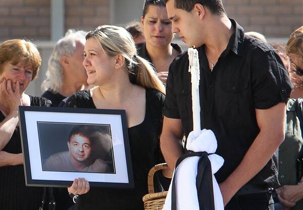 Tight bond:  Family members carry a portrait of the dead man outside St Kliment’s in  Port Kembla. Picture: KIRK GILMOUR