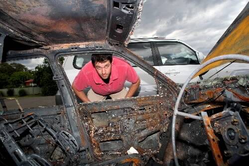 Hawks player Rhys Martin looks at his burnt-out car. Picture: GREG TOTMAN