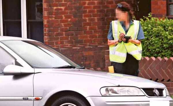A council ranger books a car in Crown St, near Wollongong Hospital, adding to the city's total of more than $1.7 million in fines. Picture: ADAM McLEAN